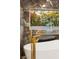 Close-up of a modern tub with marble accents, a gold faucet, and a view to the yard at 1616 Shadow Rock Dr, Las Vegas, NV 89117
