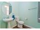 Stylish powder room with pedestal sink, round mirror, and mint walls at 2037 Brush Stroke St, Henderson, NV 89044