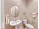 Neutral toned powder room featuring a pedestal sink and sleek, round mirror at 2114 Twin Falls Dr, Henderson, NV 89044