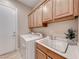 A laundry room with a utility sink, washer, dryer, and ample cabinet space above at 2114 Twin Falls Dr, Henderson, NV 89044