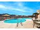 Beautiful community pool with mountain views, lounge chairs, and tables beneath yellow umbrellas at 2114 Twin Falls Dr, Henderson, NV 89044