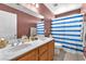 Bathroom featuring double sinks, wood cabinets, and a shower with a blue and white curtain at 2837 Canonero St, Las Vegas, NV 89142