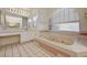 Bathroom featuring a large tub, tiled floors, double sinks, and a large arched window at 2917 Broken Willow Cir, Las Vegas, NV 89117
