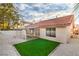 Backyard with synthetic grass area, tile roof, and a covered patio featuring white rocks at 3104 Waterview Dr, Las Vegas, NV 89117