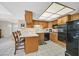 Efficient kitchen with breakfast bar seating, oak cabinetry, and black appliances at 3753 Heritage Ave, Las Vegas, NV 89121