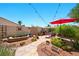 Landscaped backyard featuring a stone path, lush greenery, a patio area, and a charming red umbrella for shade at 419 Alonzo Ct, Las Vegas, NV 89123