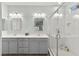Bright bathroom with double sinks, vanity with grey cabinets, and glass enclosed shower with grey tile at 424 Vigo Port St, Las Vegas, NV 89138