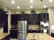 Updated kitchen with a large stainless refrigerator, granite countertops, and dark wood cabinets at 4242 Helena Hideaway Ct, Las Vegas, NV 89129