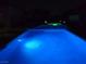 Inviting backyard pool with lights and elevated hot tub creating a relaxing nighttime ambiance at 4242 Helena Hideaway Ct, Las Vegas, NV 89129