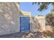 Side yard with a weathered blue gate, textured wall, and desert landscaping at 45 N Lamb Blvd, Las Vegas, NV 89110