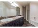 Bathroom featuring double sinks, dark cabinetry, and a separate tub and shower at 499 Kristin Ln, Henderson, NV 89011