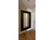 A clean hallway featuring a large mirror that accentuates space with wood-like floors and a white door at 5376 S Conquistador St, Las Vegas, NV 89148