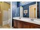 Bathroom featuring a double sink vanity with a dark wood finish, decorative wallpaper and shower-tub combo at 5747 Jaborandi Ave, Pahrump, NV 89061