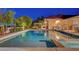 A backyard pool and spa surrounded by lush landscaping and an outdoor kitchen at dusk at 6230 Calm Brook Ct, Las Vegas, NV 89149