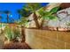 Attractive rock and masonry wall landscaping with palm trees and green foliage enhances this home's curb appeal at 733 Secret London Ave, Las Vegas, NV 89178