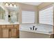 Main bathroom with a soaking tub, natural wood cabinetry, and a large mirror with excellent lighting at 733 Secret London Ave, Las Vegas, NV 89178