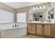 Main bathroom with a soaking tub, natural wood cabinetry, and a large mirror with great lighting at 733 Secret London Ave, Las Vegas, NV 89178