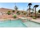 Private swimming pool with a spa surrounded by rock landscaping and green plants at 733 Secret London Ave, Las Vegas, NV 89178