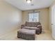 A cozy living area featuring neutral walls, carpeted flooring, a window, and a comfortable loveseat with an ottoman at 7609 Trimming Ct, Las Vegas, NV 89149
