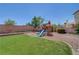 Large grassy backyard featuring a play structure with a slide and mature landscaping at 8333 Valley Stream Ave, Las Vegas, NV 89131