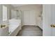 Bright bathroom showcasing a tub, glass-enclosed shower, and modern gray flooring at 8333 Valley Stream Ave, Las Vegas, NV 89131