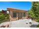 Detached structure featuring neutral stucco exterior, dual windows, double doors, and decorative white chairs on patio at 9270 Valerie Elaine St, Las Vegas, NV 89139
