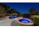 Night shot of an in-ground pool with a raised jacuzzi and blue underwater lights at 9301 Queen Charlotte Dr, Las Vegas, NV 89145