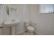 A bathroom with a pedestal sink, toilet and round mirror, lit by a window with blinds at 10198 Eden Mountain St, Las Vegas, NV 89141