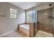 Bright bathroom with a glass enclosed shower and a soaking tub under a glass block window at 10506 Arnica Way, Las Vegas, NV 89135