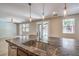 Close-up of kitchen island with granite countertop, stainless steel sink, and views to living area with ceiling fan at 10506 Arnica Way, Las Vegas, NV 89135