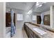 A bathroom with a dual-sink vanity, tile flooring, and a shower/tub combo with decorative tile surround at 10598 Aphrodite St, Las Vegas, NV 89183