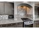 Close-up of the kitchen showcasing the granite counters, tile backsplash, and stainless steel range at 10598 Aphrodite St, Las Vegas, NV 89183