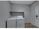 Laundry room featuring tile flooring, a modern washer and dryer, and a shelf at 10598 Aphrodite St, Las Vegas, NV 89183