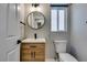 Bathroom features a modern vanity, round mirror, and a window that provides natural light at 10908 Royal Highlands St, Las Vegas, NV 89141