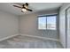 Bright bedroom features neutral walls, plush carpet, ceiling fan, and a window with neighborhood views at 10908 Royal Highlands St, Las Vegas, NV 89141