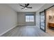 Spacious bedroom with wood-look floors, ceiling fan, a window and ensuite bathroom with sliding barn door at 10908 Royal Highlands St, Las Vegas, NV 89141