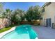 Sparkling in-ground pool surrounded by a concrete patio, lush trees, and a privacy fence at 10908 Royal Highlands St, Las Vegas, NV 89141