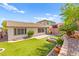 Backyard featuring artificial turf, a brick perimeter wall, a fire pit, and tasteful landscaping in a serene setting at 11764 Golden Moments Ave, Las Vegas, NV 89138