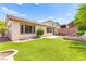 Backyard showcasing a well-maintained artificial lawn, a brick patio and block perimeter wall with a fire pit at 11764 Golden Moments Ave, Las Vegas, NV 89138