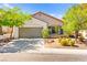 Charming single-story home with a well-manicured lawn, mature trees, and an attached two-car garage at 11764 Golden Moments Ave, Las Vegas, NV 89138