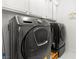 Modern laundry room featuring a sleek, front-loading washer and dryer set with overhead cabinet storage at 11764 Golden Moments Ave, Las Vegas, NV 89138