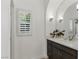 Bathroom vanity with an elegant arched mirror and a shuttered window at 11775 Woodbrook Ct, Las Vegas, NV 89141