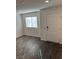 Bright living room with gray vinyl flooring, a window, and a white front door at 12170 Midnight Pine Rd # 3, Las Vegas, NV 89183