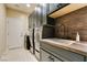 Modern laundry room with dark cabinets, sink, countertop, and stainless steel washer and dryer at 124 Strone St, Henderson, NV 89012