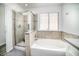 Bright bathroom features a soaking tub and glass enclosed shower with beige stone surround at 1512 Bellglen Dr, Las Vegas, NV 89128