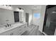 Bright bathroom featuring a double vanity, a shower, and wood look flooring at 1580 S Tiptop Trl, Pahrump, NV 89048