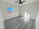 A simple bedroom features a ceiling fan, wood-look floors, and a sunny window at 1580 S Tiptop Trl, Pahrump, NV 89048