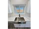 Close-up of stainless farmhouse sink with black faucet beneath window with backyard view at 1580 S Tiptop Trl, Pahrump, NV 89048