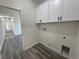 Laundry room access from hall features white cabinets, hookups, and gray floors at 1580 S Tiptop Trl, Pahrump, NV 89048