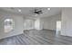 Open-concept living room featuring large ceiling fan, gray wood floors, and natural light at 1580 S Tiptop Trl, Pahrump, NV 89048